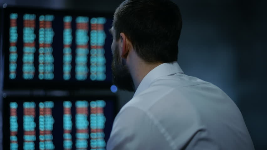 Late at Night Trader Reads Numbers on His Multiple Displays with Stock Information on Them. In Background Big City Window View. Shot on RED EPIC-W 8K Helium Cinema Camera. Royalty-Free Stock Footage #26897080
