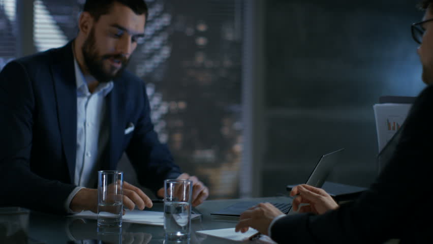 Late at Night Businessman Businessman Has Conversation with Important Client, They Come to an Agreement, Sign Contract and Shake Hands. In the Background Big City Window View. Shot on RED EPIC-W 8K. Royalty-Free Stock Footage #26897113