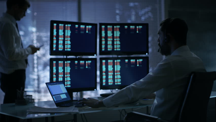 Late at Night in Trader's Bureau. Stockbroker Reads Numbers on His Multiple Displays with Stock Information on Them,He Also Consults Clients with Headset On. | Shutterstock HD Video #26897146