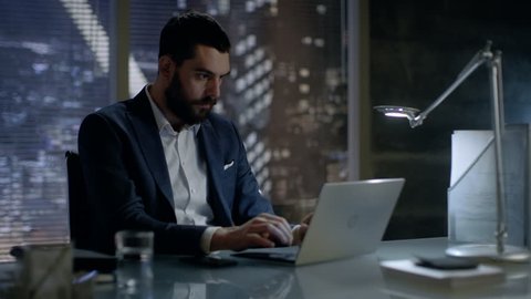 Late at Night Businessman Works on a Laptop in His Private Office with Big City Window View. Shot on RED EPIC-W 8K Helium Cinema Camera.