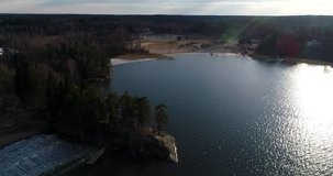 Oittaa, Cinema 4k aerial landing view behind trees at Oittaa beach, at bodom lake, on a sunny spring day, in Espoo, Finland