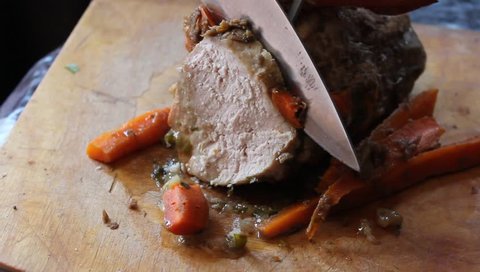 Video knife cuts a piece of fresh delicious juicy flavor grilled meat. Pork with vegetables & herbs in a spicy sauce. Fragrant roast pork, red carrots & garlic Festive carvery lunch Food after fasting
