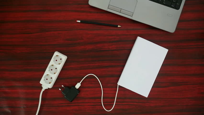 Person connecting a book to a power strip through a USB charger. Battery symbol indicating the charge level. Royalty-Free Stock Footage #26914900