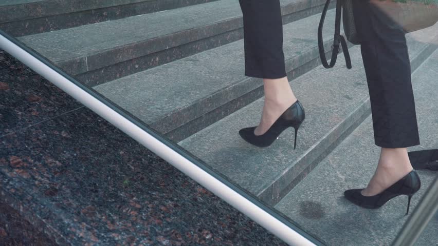 Lower part of business woman in formal suit walking up the outdoor stair.