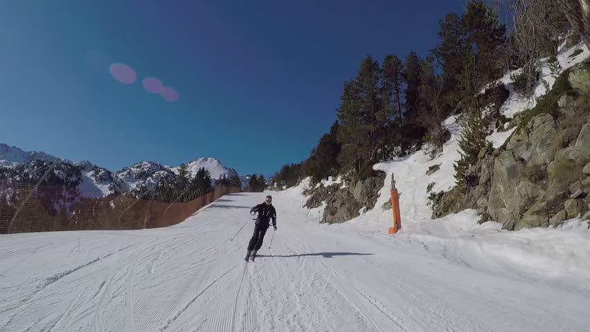 On a Sunny winter's day, a skier in a black suit rolls a carving ski on the ski slope in the mountains, it is removed on the action camera Royalty-Free Stock Footage #26917384
