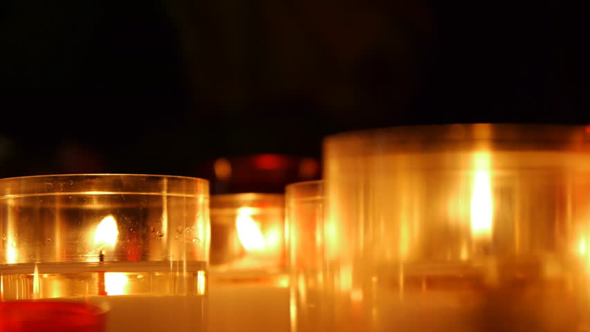Illuminated candles in a church in white, red and yellow colors