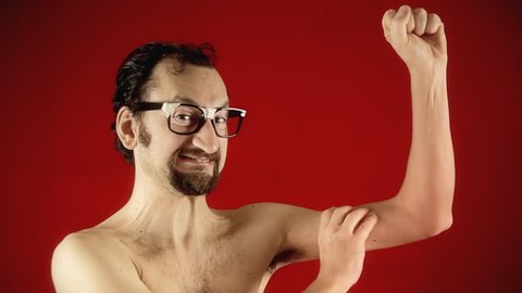 A funny ugly slim nerd man, showing the strength of his muscles by flexing them, half naked.
