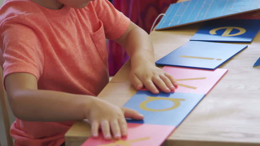 Pupil Working At Desk With Letters On Wooden Shapes