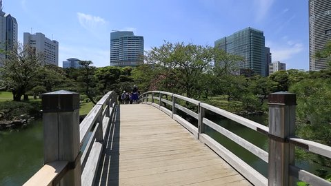 Tokyo, Japan -April 20, 2017:Wooden path in Hamarikyu Gardens with buildings of Shiodome-Shimbashi District background. Hama Rikyu is a large beautiful landscape garden in Chuo district, Sumida River