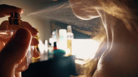 Beautiful woman spraying perfume on her neck. Slow motion close-up video