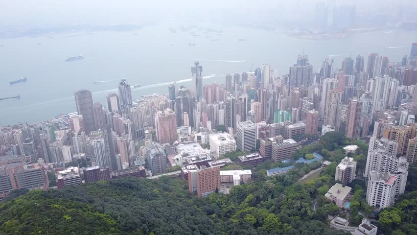 Sai Ying Pun, Western District of Hong Kong panoramic aerial view, light haze in air. Victoria harbour waters after dense developed area, west kowloon district seen on opposite shore, seen through fog