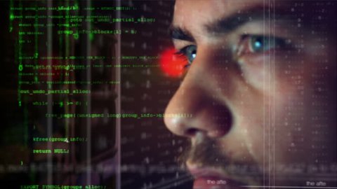 Male hacker working on a computer for cyber attack while green binary hacking code characters reflect on his face in a dark office room - industry 4.0 concept