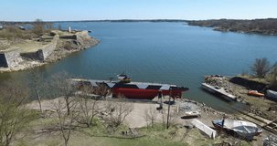 Aerial drone footage of Suomenlinna Sveaborg bastion fortress and lagoon on Baltic Sea with cannons, submarine and boats in bright spring day near Helsinki the capital of Finland, northern Europe