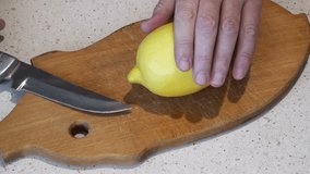 Male hands cut a lemon on lobules on a wooden board. Full HD 1920x1080 Video Clip