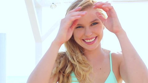 Happy blonde bikini girl on holiday vacation at the beach - hand held shot