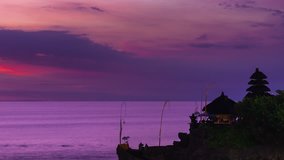 4K Timelapse. One of the main popular attractions of tropical island Bali  / hindu sea temple tanah lot bali indonesia at the sunset sun reflecting on the ocean / Bali, Indonesia