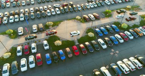 New car dealership lot, many vehicles for sale, aerial view.
