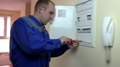 young man electrician work on the main circuit breaker in living room. Profession. 4K