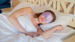 4k video of beautiful young woman taking off blindfold sleeping mask and sitting on bed