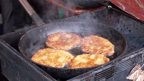 Potato pancakes are fried in a frying pan on the grill. Full HD 1920x1080 Video Clip