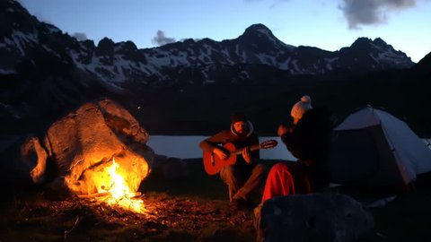 Couple of travelers at dusk near a campfire, romantic atmosphere
