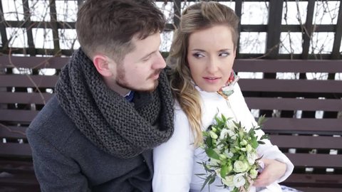Loving couple sitting on a bench in winter. Guy and girl kissing. The bride and groom kiss. Beautiful couple kissing. Love