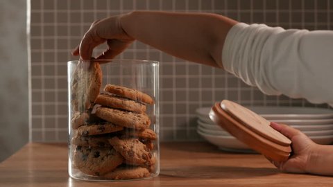 Young child taking a cookie from a cookie jar in a kitchen. 
