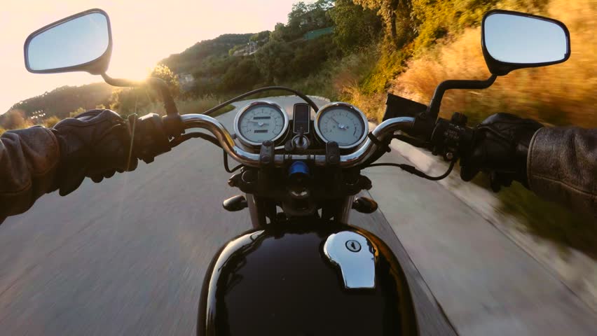 POV of masculine and manly motorcycle driver driving his vehicle through the windy mountain empty road in beautiful scenery on summer day full of thrilling adventures, with light leaks and flares