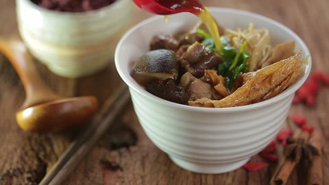 Bak-kut-teh is a pork rib dish cooked in broth popularly served in Malaysia and Singapore and Southern Thailand. Chinese hot soup with herbs on rustic wood.