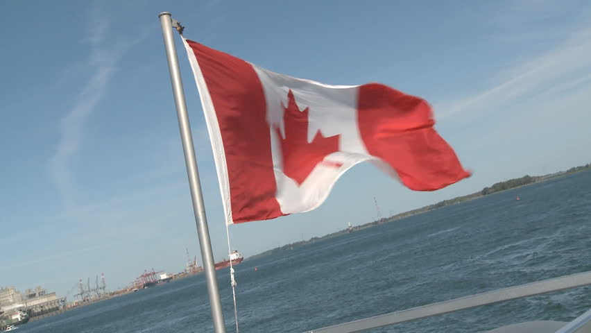 Canadian flag flies in the wind from a taffrail pole over the bay near Montreal 