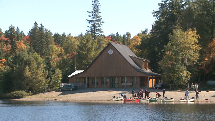 Group of people getting ready for boating with canoes on a lake in a peaceful nature scene