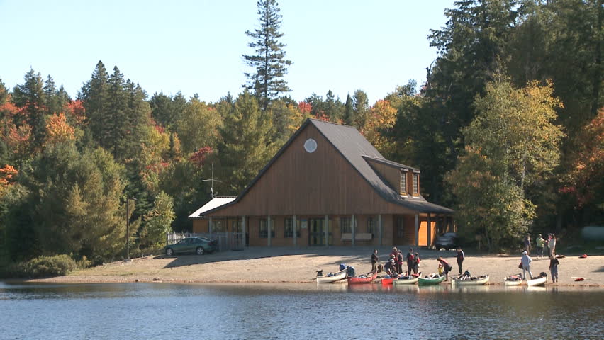 Group of people getting ready for boating with canoes on a lake in a peaceful