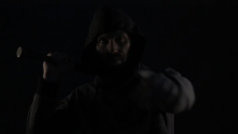 bandit, hooligan or football fan with baseball bat attacks on dark background