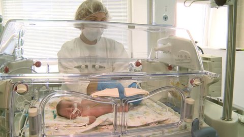 Russia. In October of 2015. Newborn baby lying in an incubator in intensive care in the hospital.Nurse of perinatal center cares .