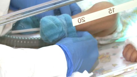 Newborn baby lying in an incubator in intensive care in the hospital.Nurse of perinatal center cares .