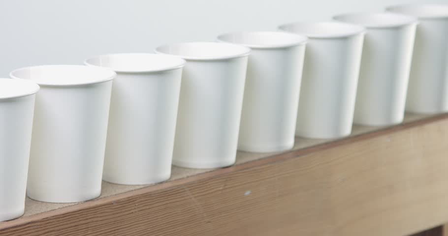 row of white blanc paper cups goes to unfocus on the wooden table