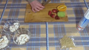 Girl cuts a strawberry on a cutting board. On the table is an orange, strawberries, kiwi, nuts. Whipped cream. A metal knife. Food video. Waffle cup. Making ice cream sundae: vanilla ice cream.