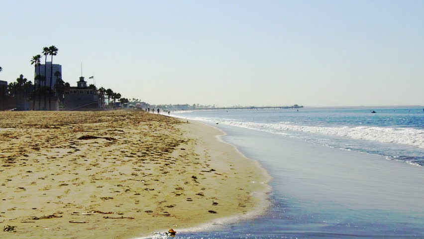 A mature man jogs on a Southern California beach away from the camera. 