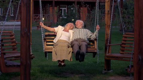 Man and woman outdoors, evening. Happy couple on porch swing. How to find love.