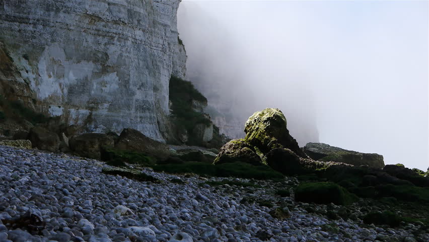 Steep cliffs at the rocky beach with mist. The shot is taken near Etretat,