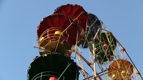 Ferris wheel rotates on blue sky background close-up