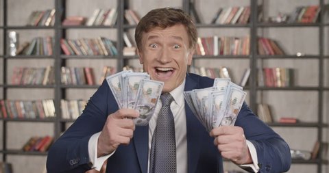 Great Winning! Slow Motion Portrait of Very Happy Successful Cheering Man Throwing Money Up, Rising Hands Celebrating His Successful Win With a Lot of Dollars. Businessman Series. 4K UHD 4096x2160.