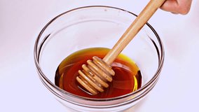 Video footage of honey dripping into a bowl on the table, isolated on white background