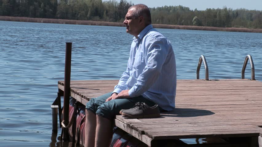 Man relaxing on the edge of the lake footbridge