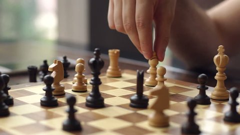 Close-up of the hand of a man playing chess. Close-up of man who is making move in chess game. Man and woman playing chess in a cafe. Slow motion.
