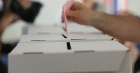 Man hand casts a ballot as she votes for the local elections at a polling station.