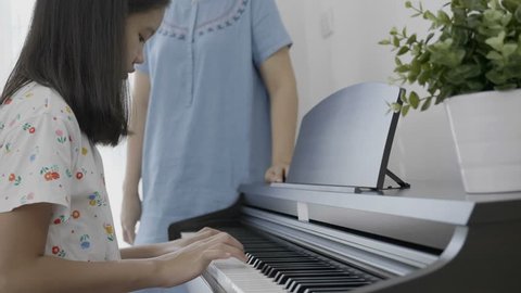 4K : Slow motion of Asian girl playing piano with her mother