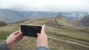 woman uses a smartphone to video a beautiful view in the mountains