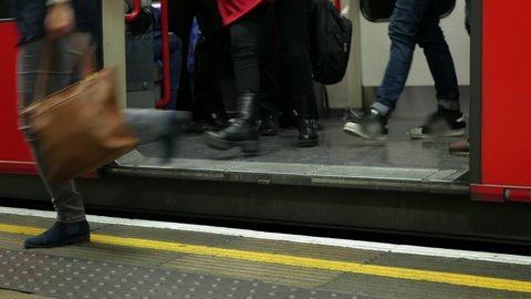 People getting off a tube train in London.
A tube train on the London Underground stopping at a platform, the door opens and people get off.