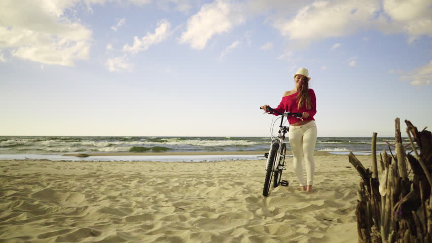 Young long hair woman enjoying windy summer day on sandy beach dunes  Active girl with bicycle on seaside. Female tourist resting near to sea  on fresh air 4K ProR es HQ codec